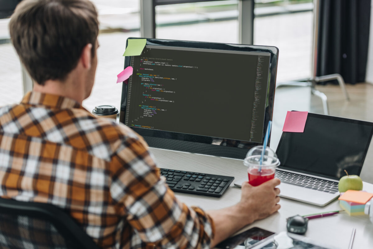 back-view-of-young-programmer-holding-glass-of-juice