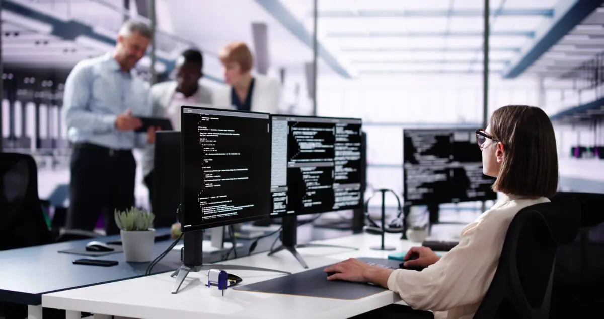 woman coding on multiple monitors