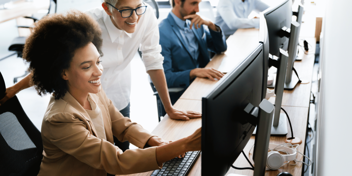Two smiling women using AI skills and tools at a computer in the office