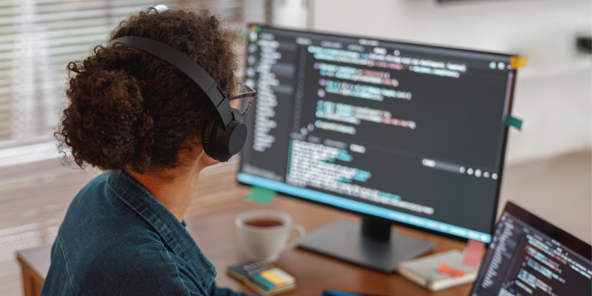 Programmer coding with a monitor and an open laptop side by side