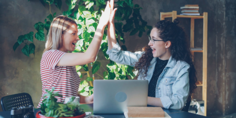 two women high-fiving, working through an intensive coding bootcamp